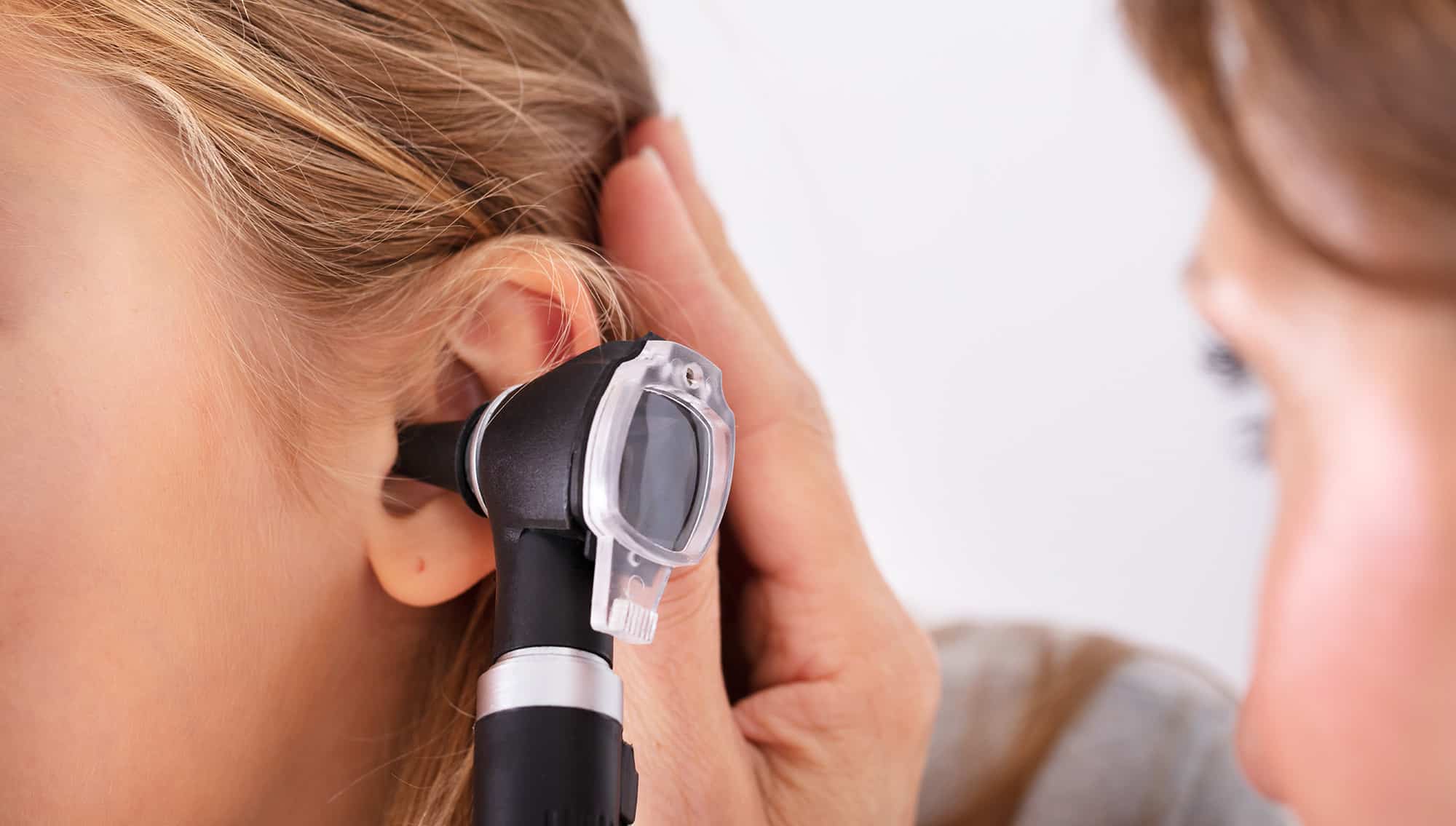 general practitioner checks a patient's ears