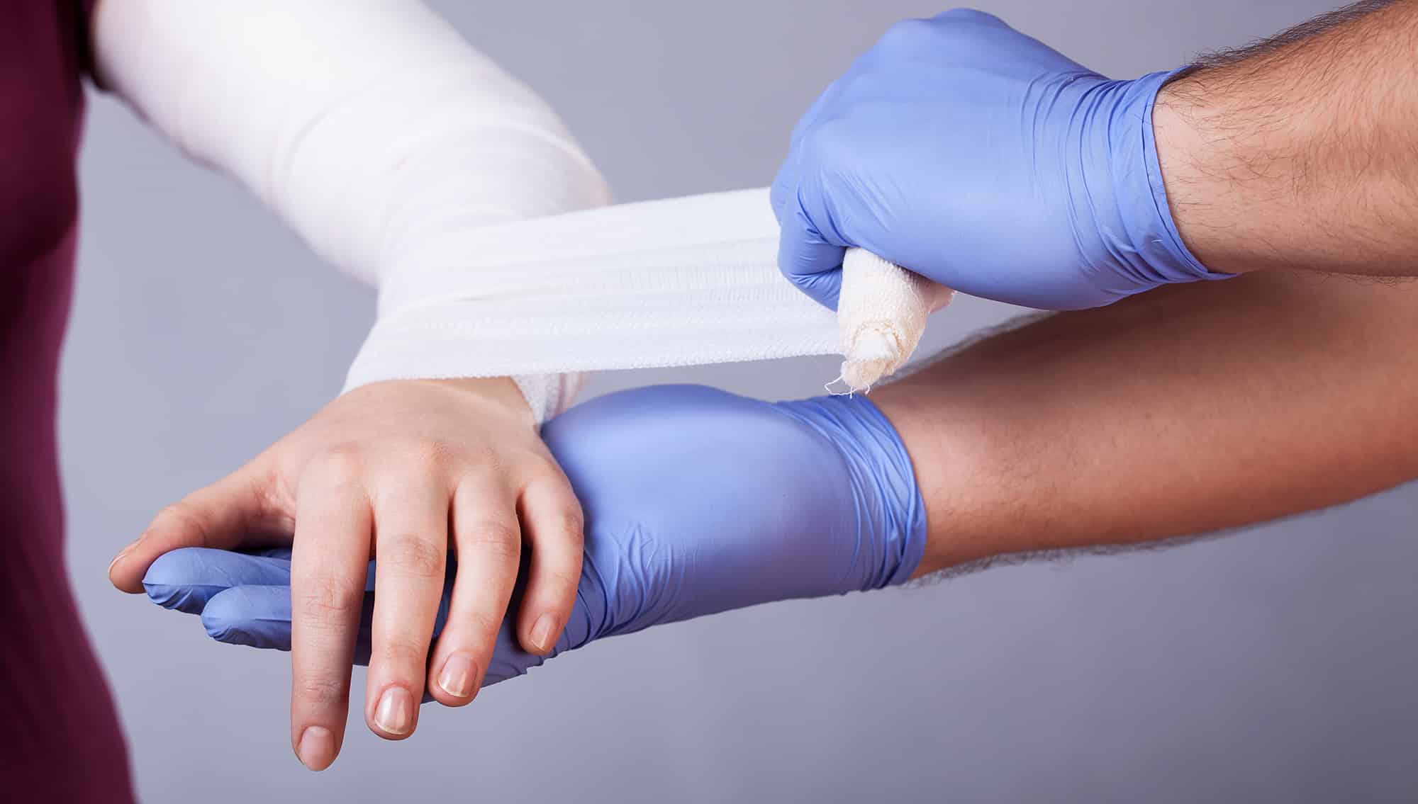 general practitioner wrapping an arm in bandages